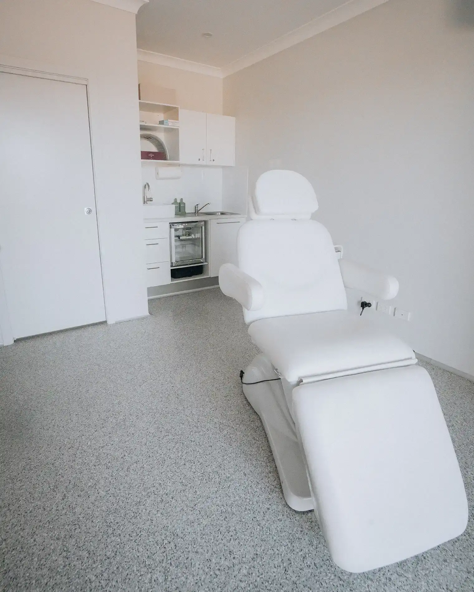 The reclining white treatment chair in the clinic room at Enrich Aesthetics, Wangi Wangi