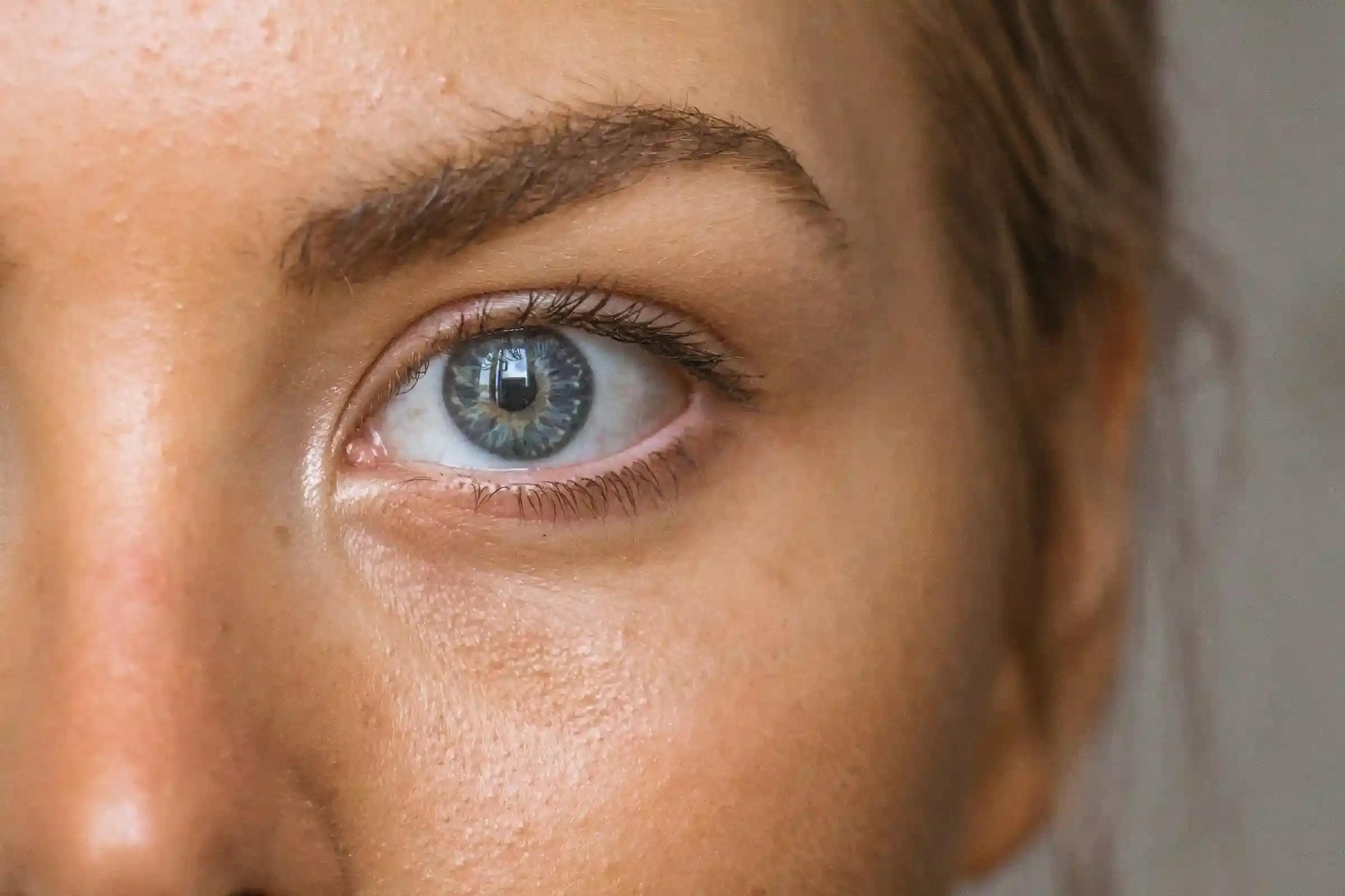 Close detail of the skin around a woman's eye, showing surface texture and fine dry patches