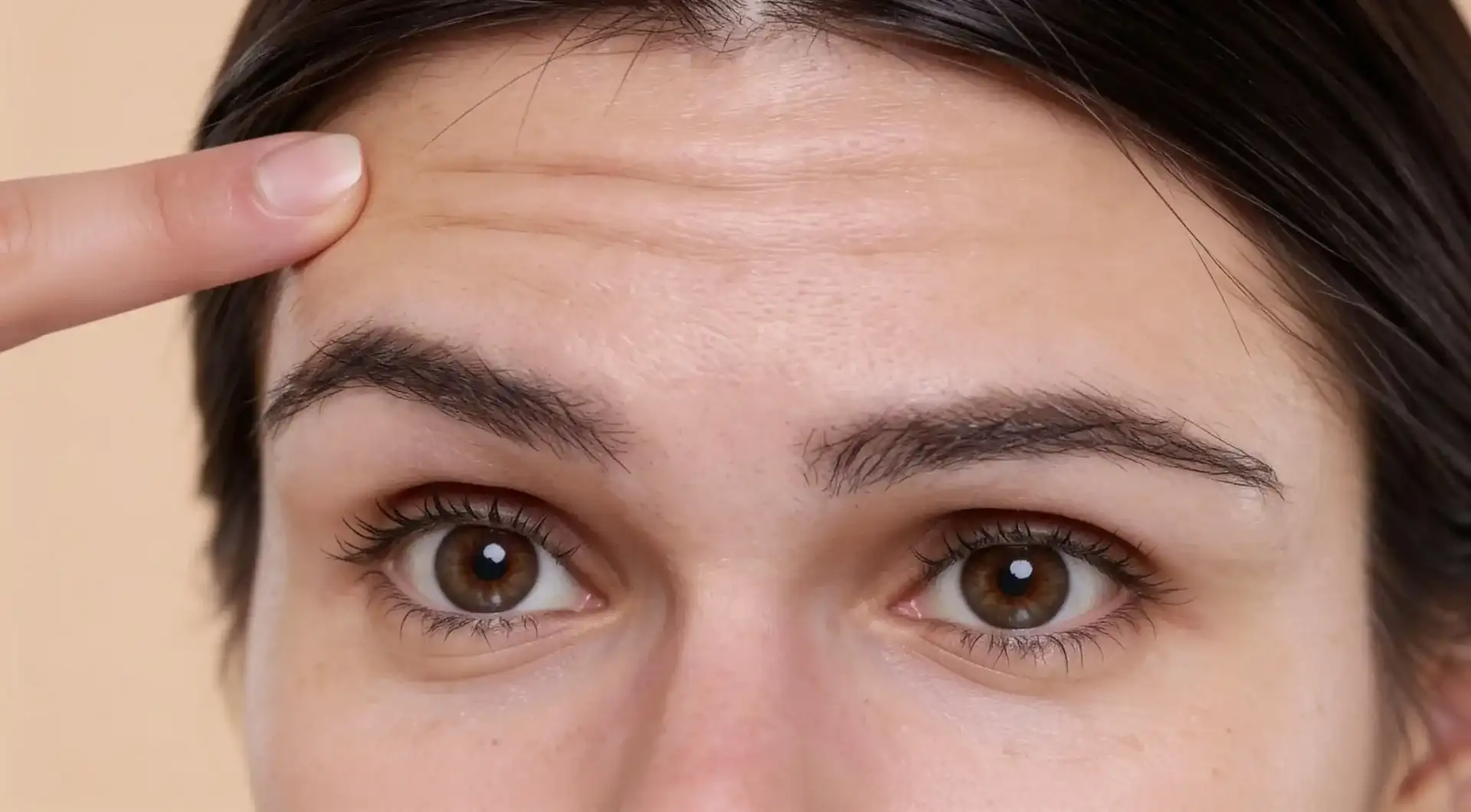 A woman pointing to a horizontal line across her forehead