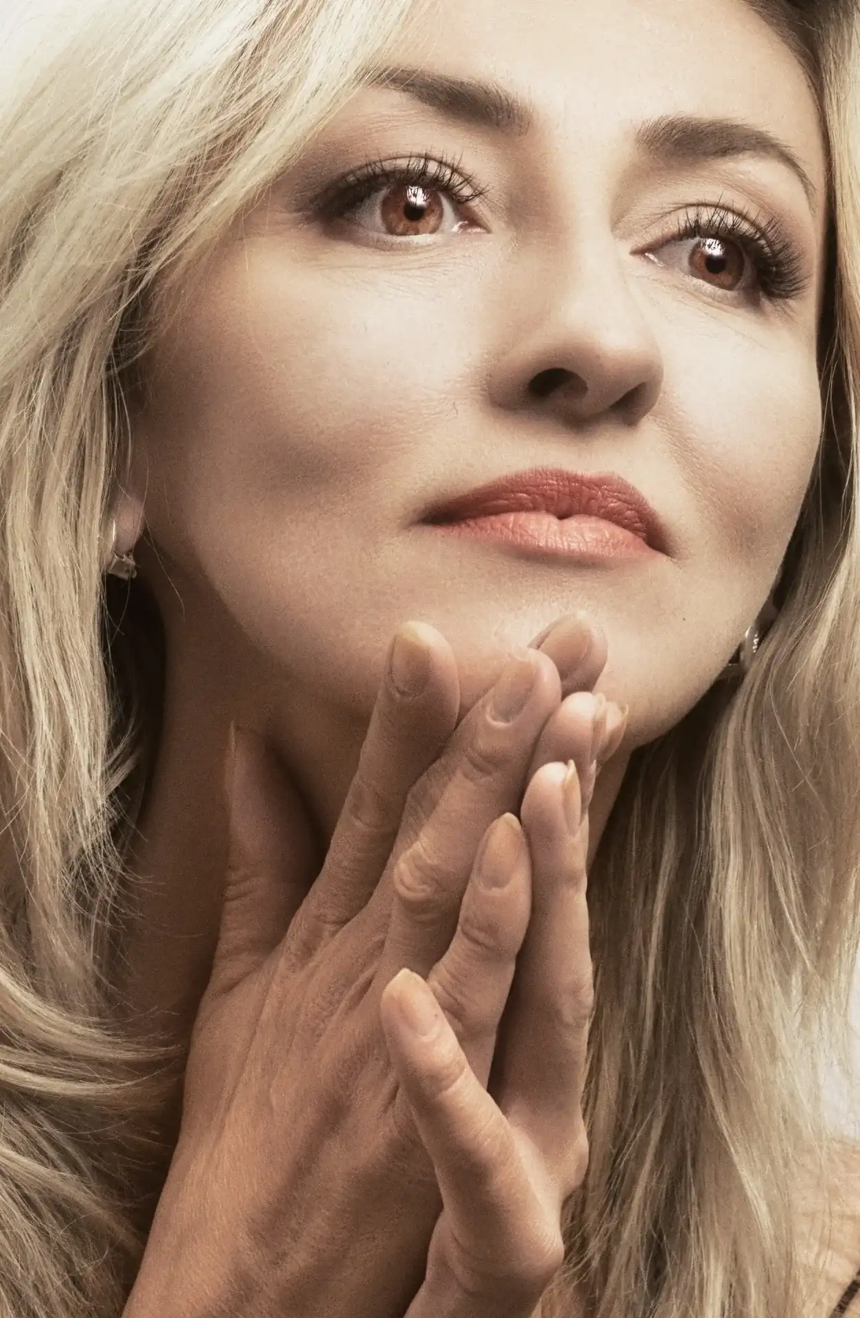 A woman resting her hands near her face, with natural expression and facial movement